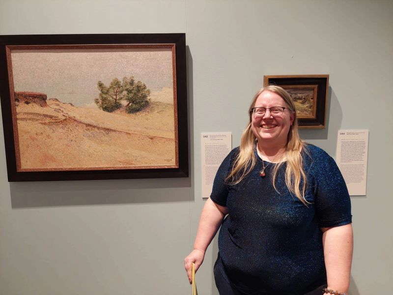 Nora Bosscher in een museumsetting naast een schilderij